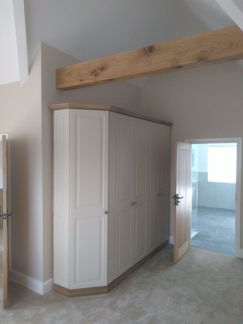 Finished bedroom with a fitted wardrobe, painted walls and an oak beam
