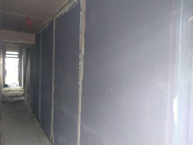 Corridor with new plasterboard fixed to the walls, ready for skimming