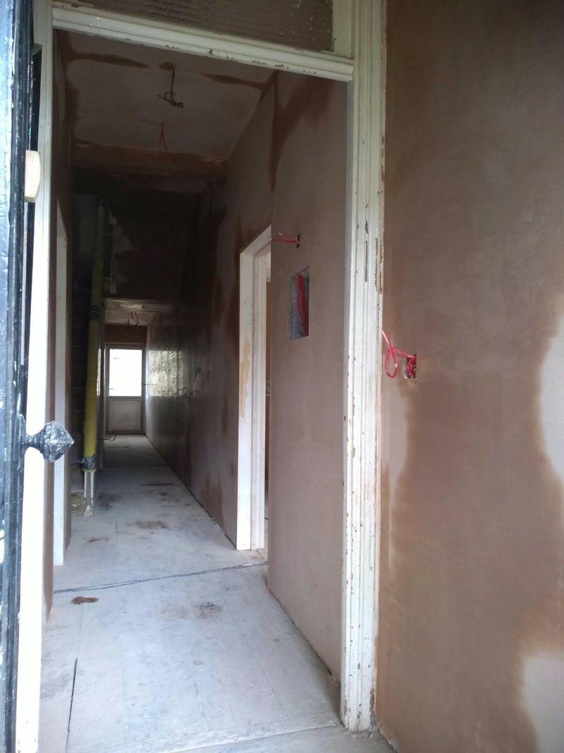 Long hallway with newly plastered walls and doorways