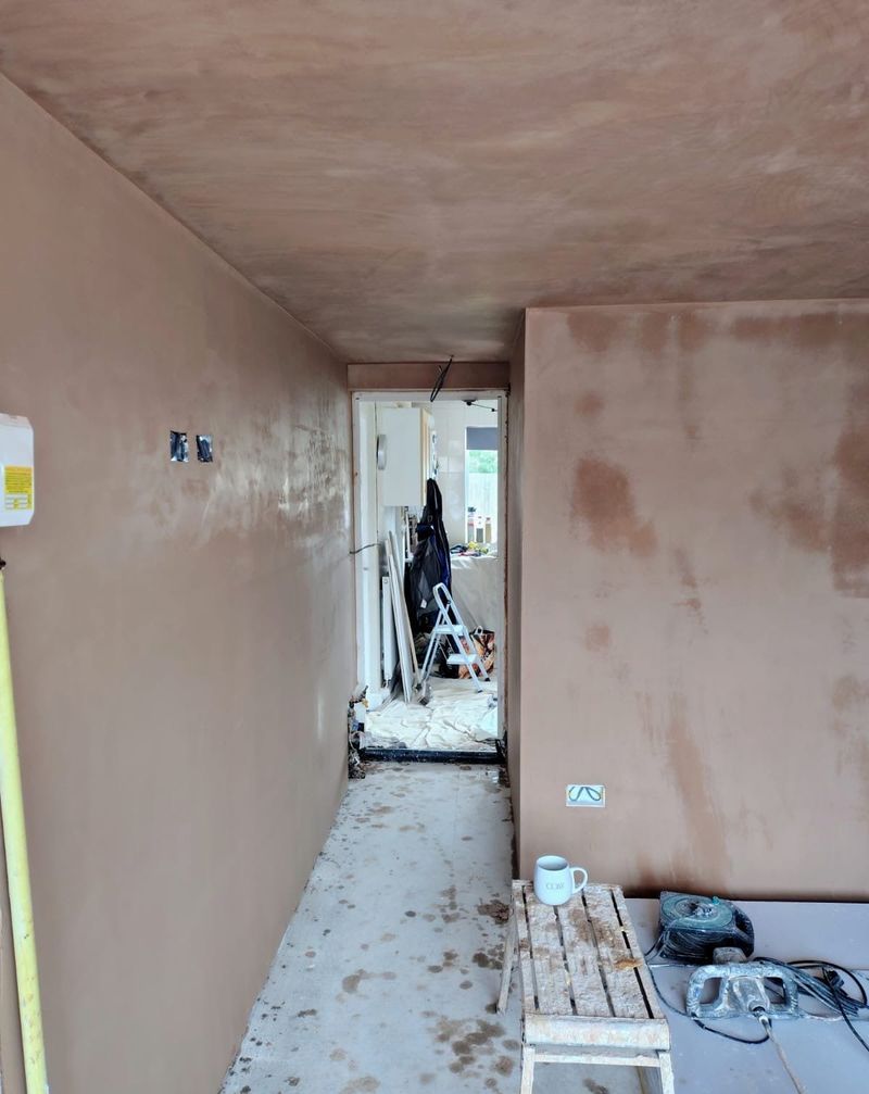 Freshly plastered walls and ceiling with plastering tools and a step on the floor