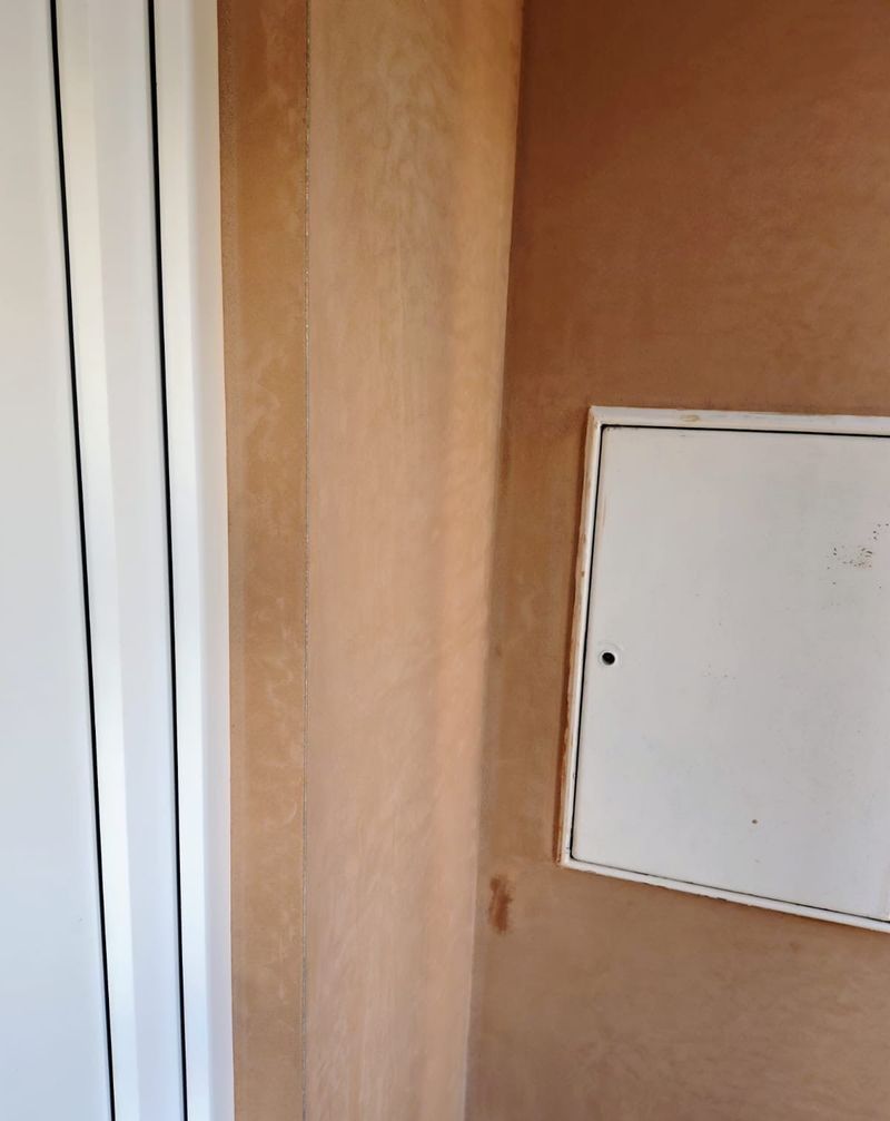 Freshly plastered wall beside a door, with a white access panel fitted
