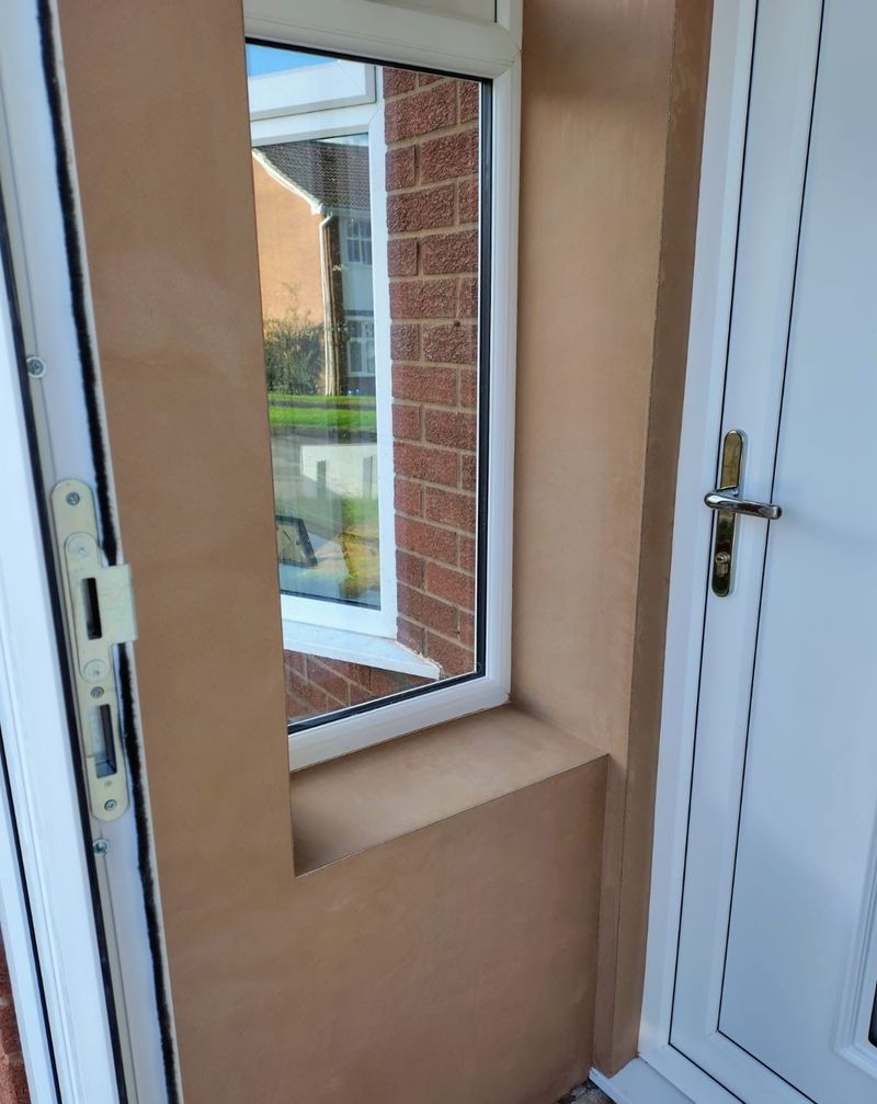 Newly plastered wall and window reveal beside a white front door